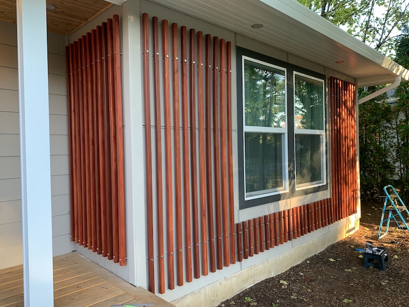 Picture of slatted fascia on front of a house surrounding a window, finished in red sealant.