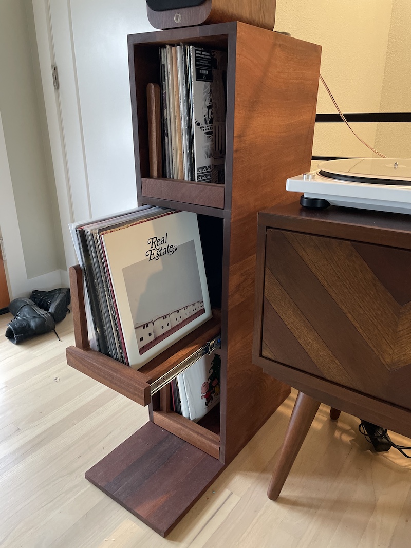 A record cabinet that features pull out drawers showing records stacked at a flipping angle.